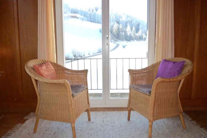 Zwei bequeme Korbstühle am Fenster mit Blick in die Natur